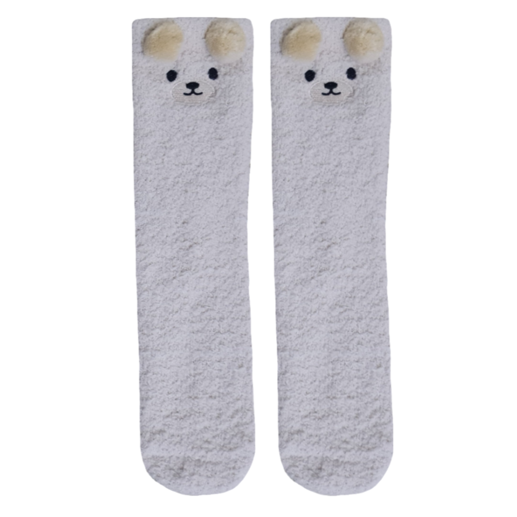 A pair of beige, fluffy socks with a cartoon bear face and ears on top.