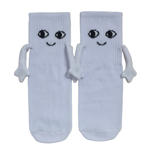 Pair of white kids magnetic hand-holding crew socks with stitched 3D cartoon eyes, happy smiles, and small plush magnetic arms holding hands.