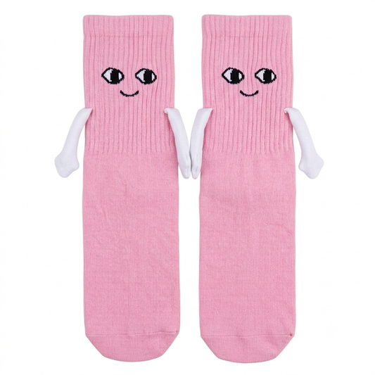 A pair of pink crew socks with embroidered cartoon eyes and smiles on the cuffs, plus small white arm details, shown on a plain white background.
