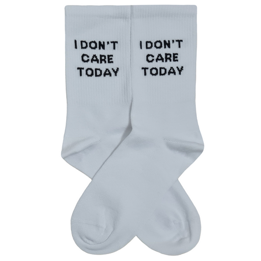 A pair of white crew socks laid flat against a white background, featuring the text "I DON'T CARE TODAY" knitted in blocky black letters below the cuffs.