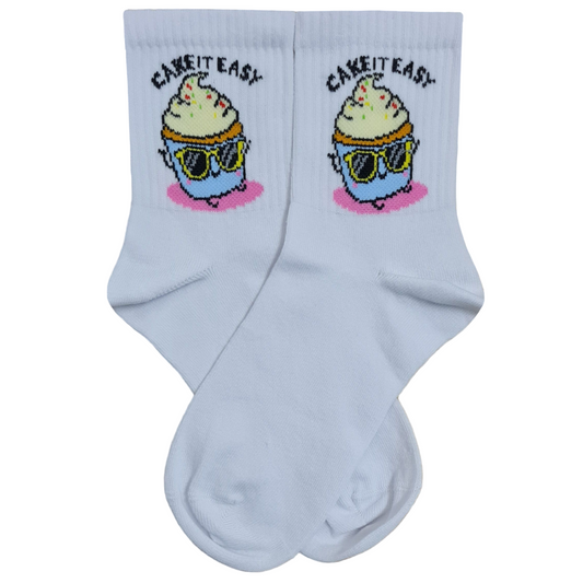 A pair of white quarter crew socks featuring a cartoon cupcake wearing sunglasses with the text Cake It Easy printed above it.